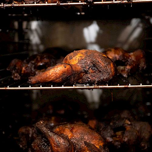 Three racks of roasted poultry in an oven, showing well-cooked, browned birds in different stages of roasting.