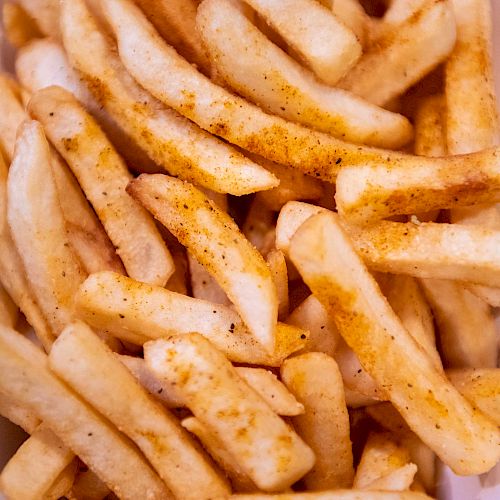 The image shows a pile of seasoned French fries, likely sprinkled with a seasoning blend, on a white plate.