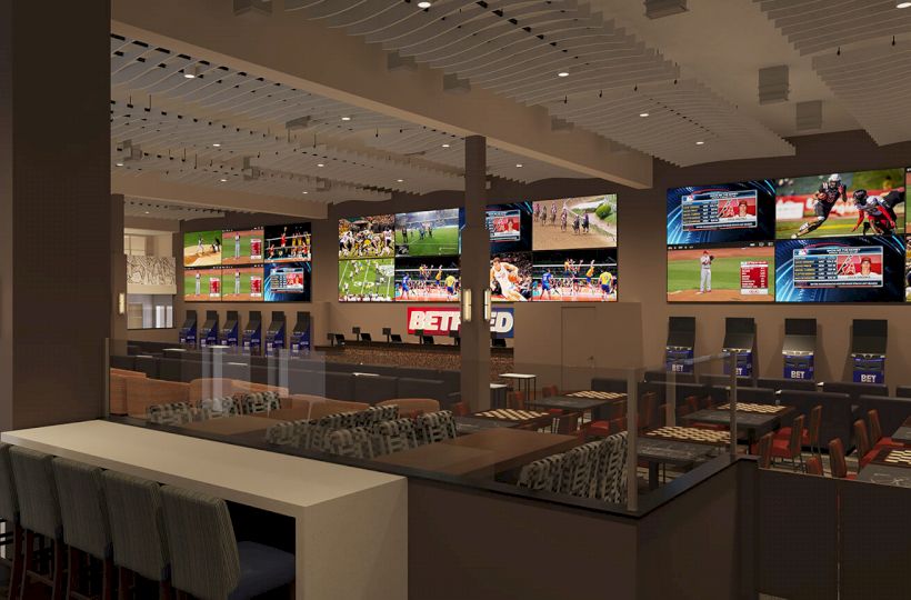 A sports bar/lounge with multiple large screens showing different sports events, comfy seating, and betting terminals.